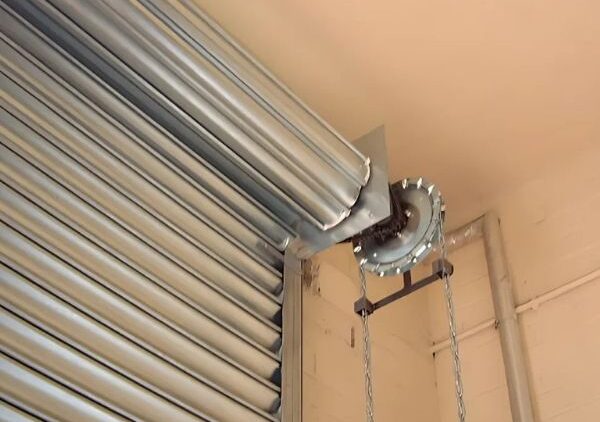 Zincirli manuel sistemle çalışan, kapalı pozisyonda bir sac kepenk ve yukarıda yer alan sarmal mekanizması.